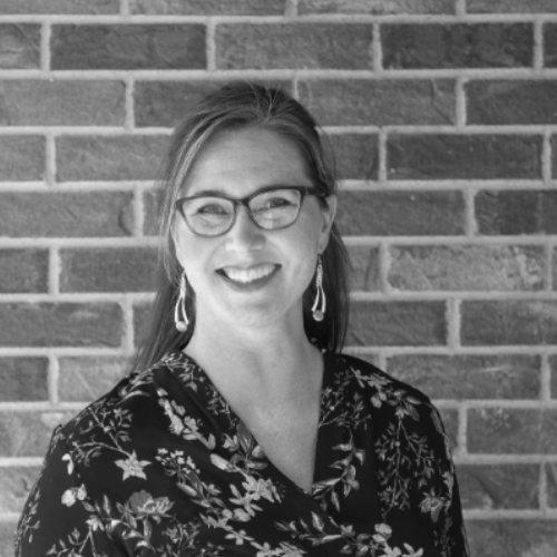 Woman wearing glasses smiling at the camera. 